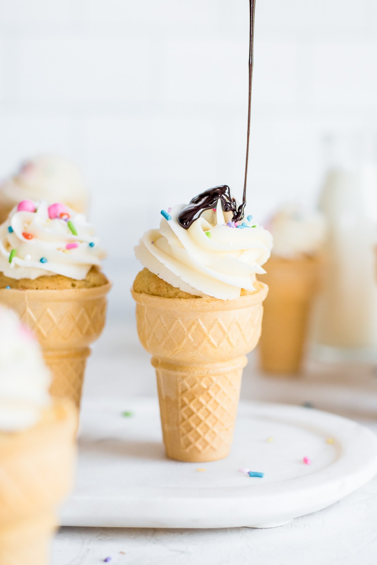 chocolate sauce being drizzled on frosting