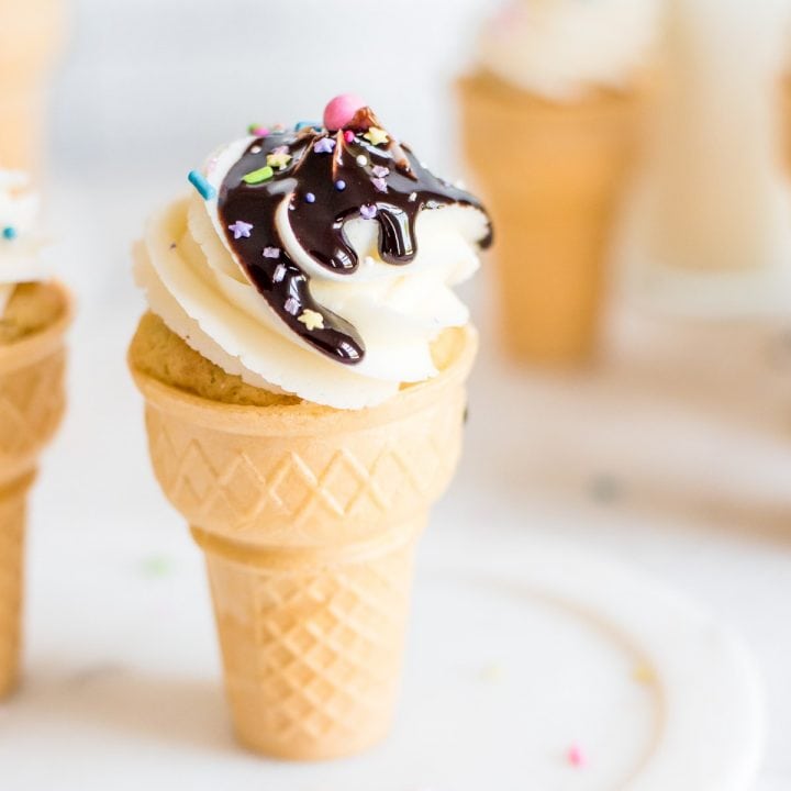 ice cream cone filled with cupcake and topped with frosting and chocolate sauce