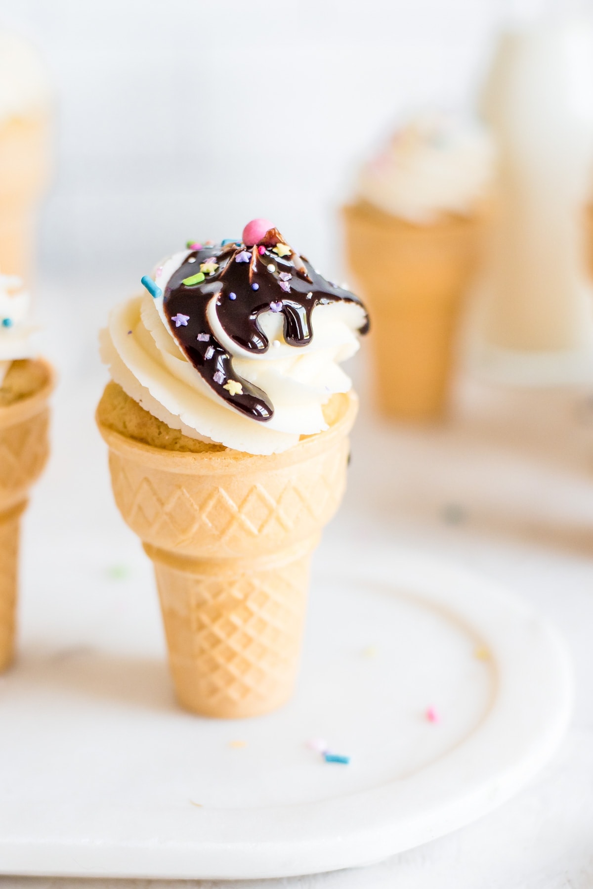 ice cream cone filled with cupcake and topped with frosting and chocolate sauce