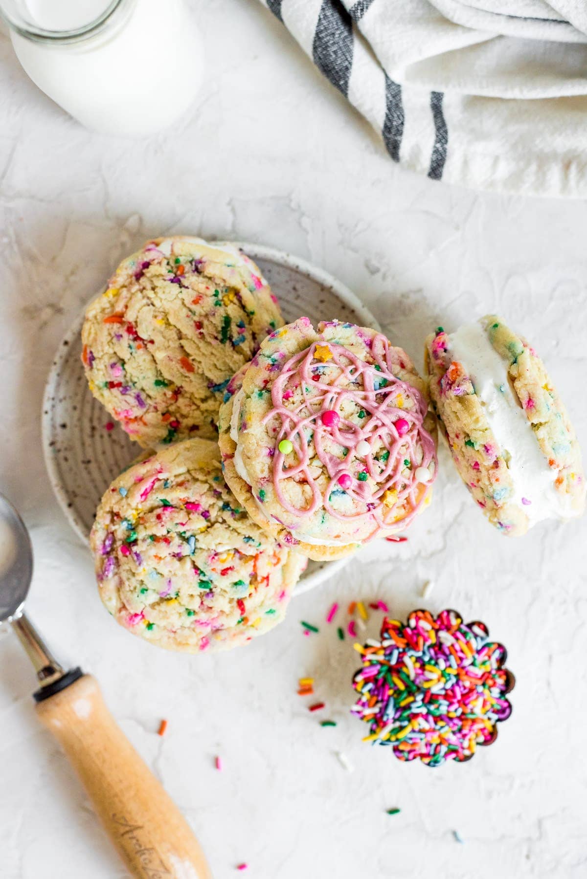 overhead ice cream sandwiches piled on plate next to small bowl of sprinkles