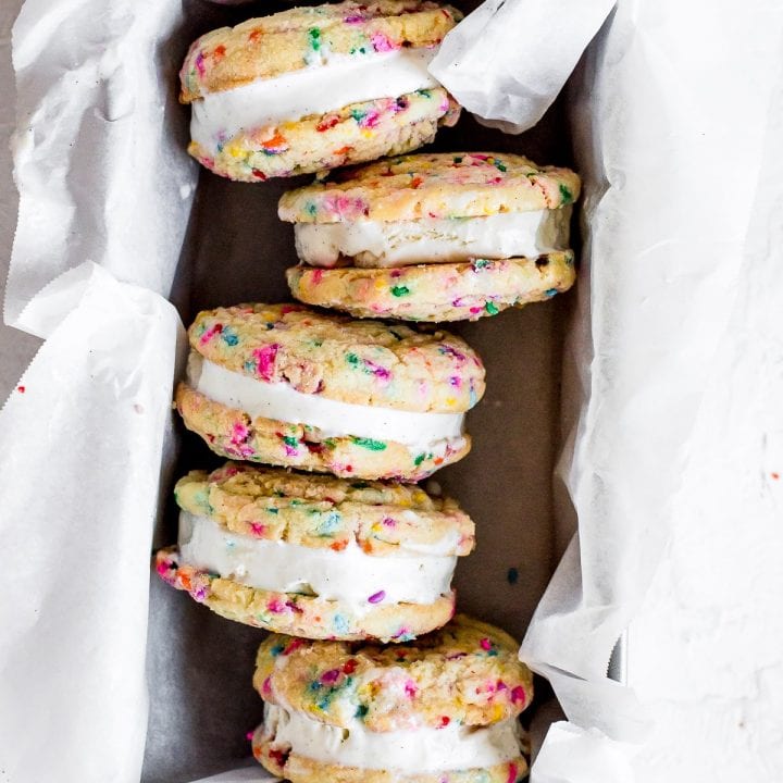 sugar cookies sandwiching ice cream in pan with parchment paper on bottom
