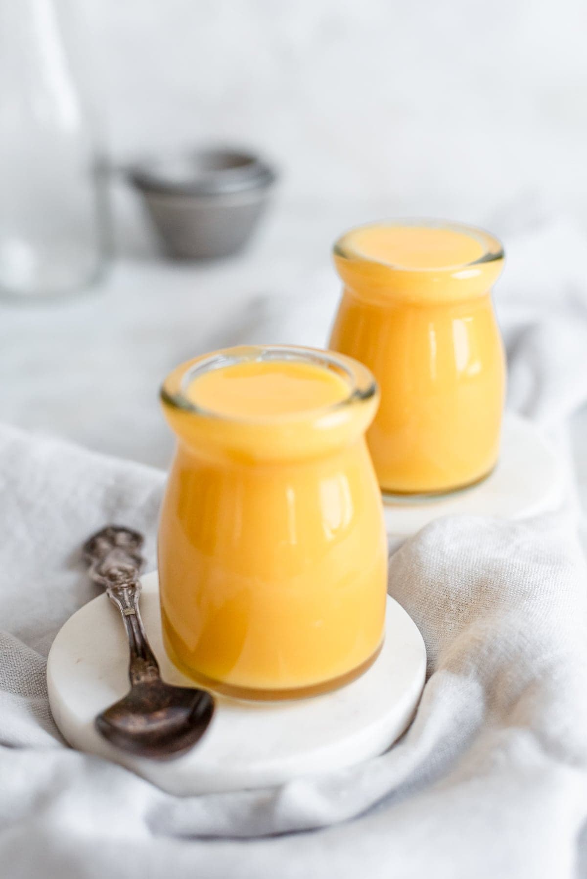 jars of fruity curd on coasters with a grey kitchen towel