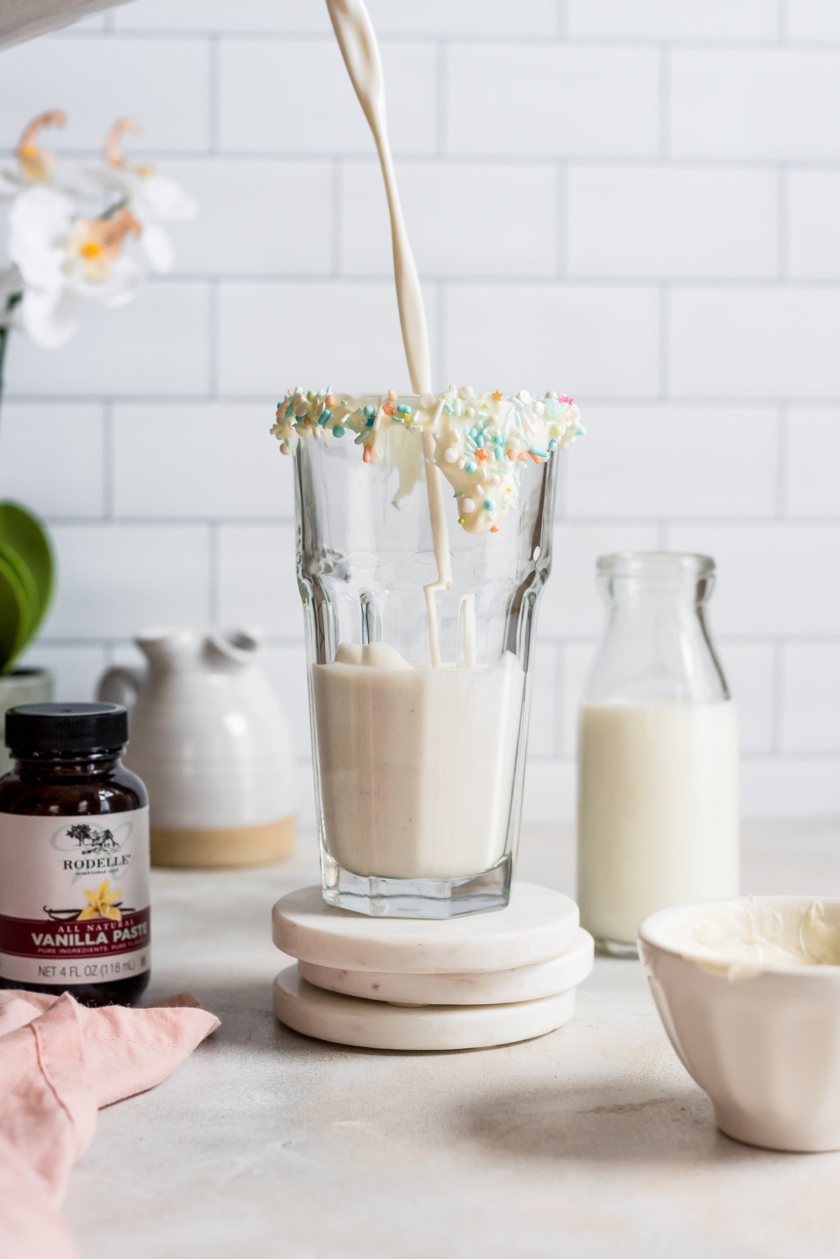 pouring vanilla milkshake into glass