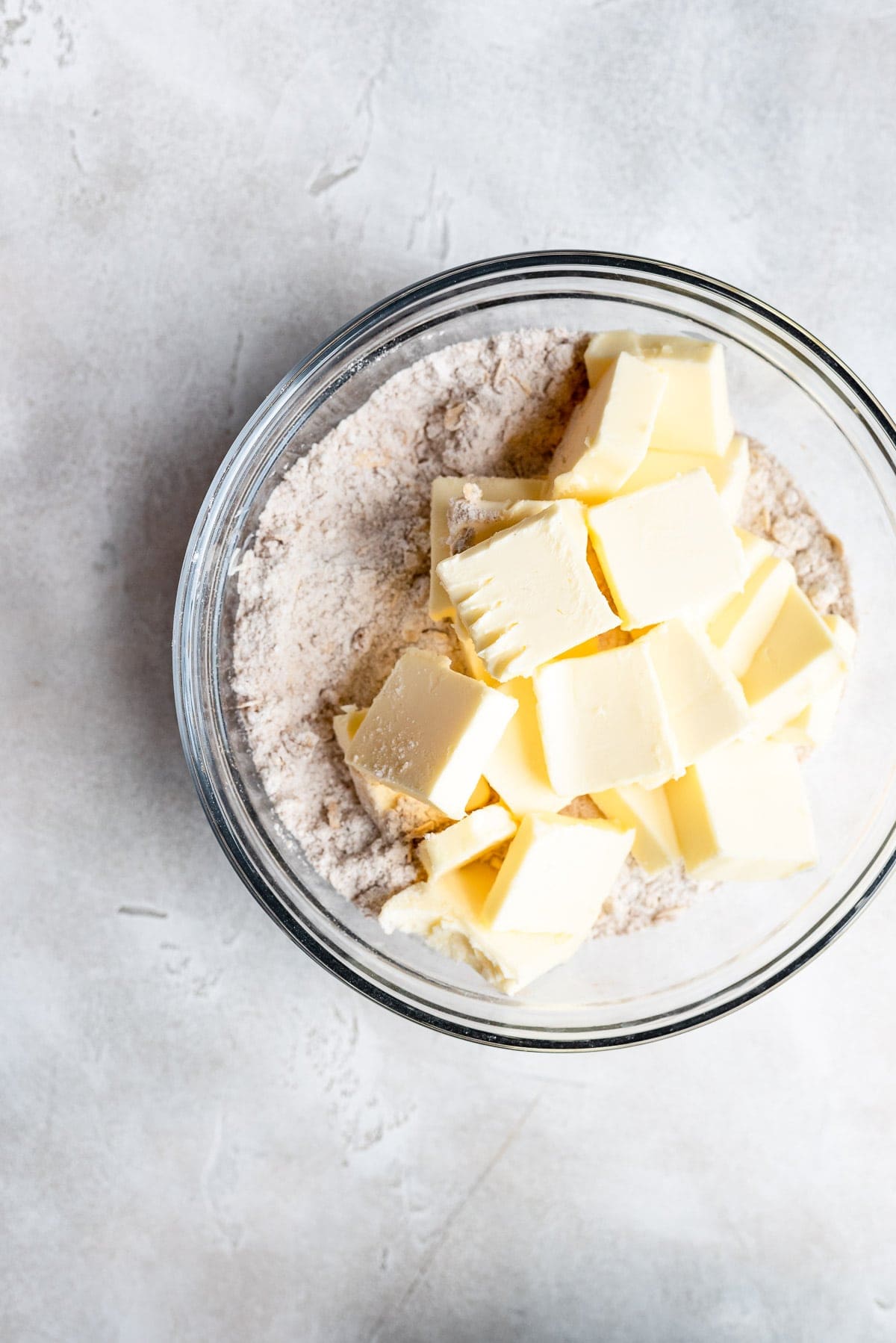 adding butter to dry ingredients in a bowl