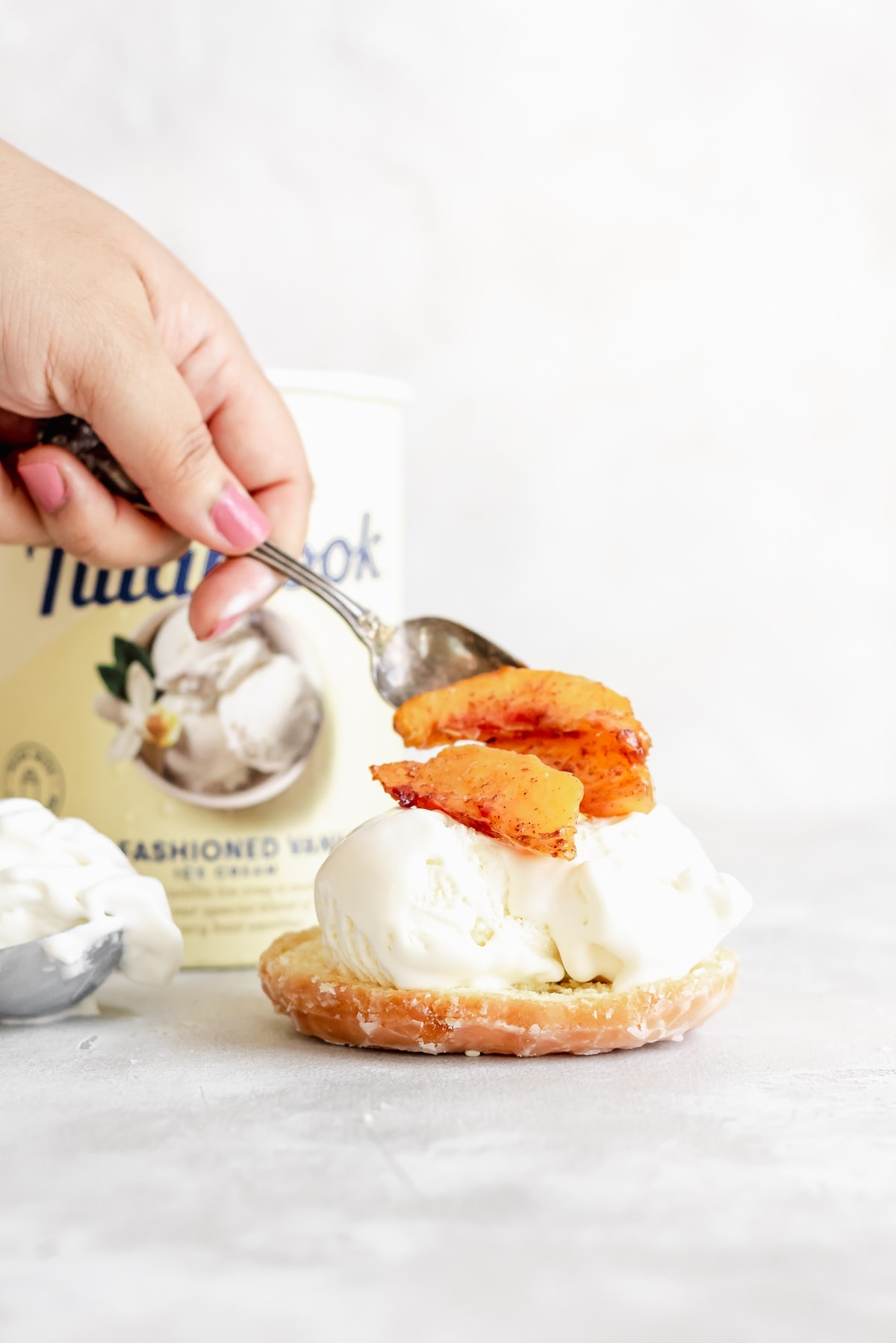 adding peaches on top of ice cream on top of donut