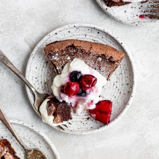 slice of cake on white plate topped with whipped cream and berries