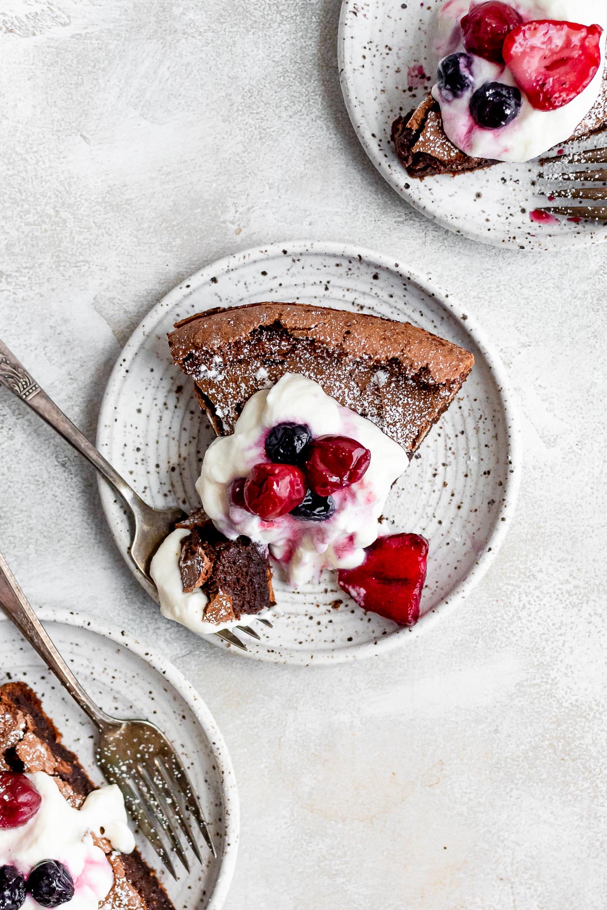 slice of cake on white plate topped with whipped cream and berries