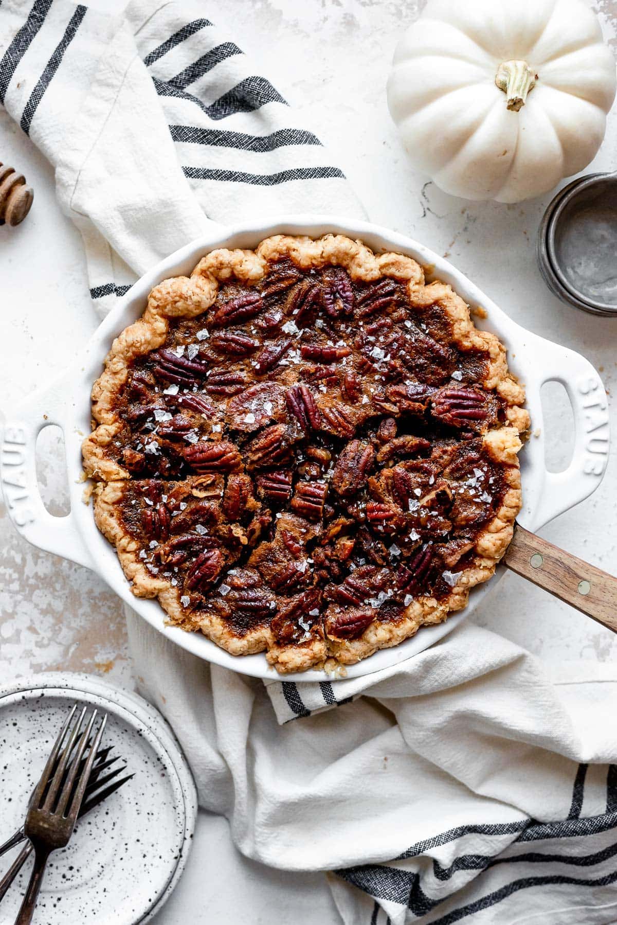 pecan pie in pie tin with pie server next to tea towel