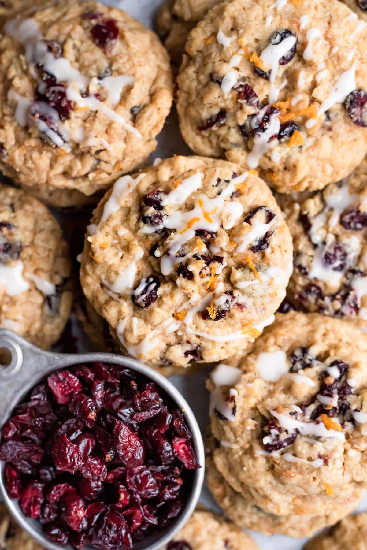 cookies close up drizzled with white chocolate next to bwol of cranberries