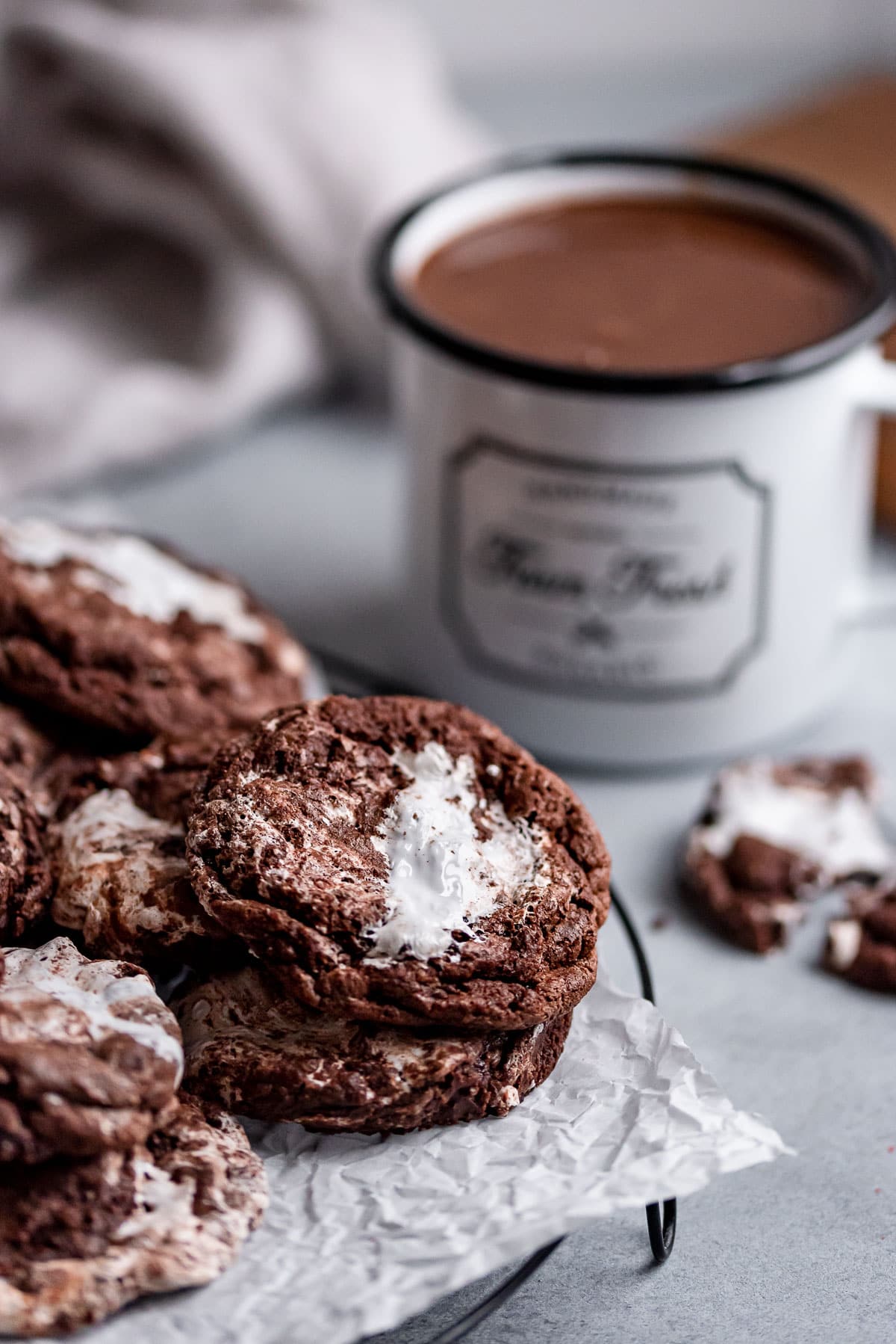 hot chocolate cookies stacked on wire rack next to mug of hot chocolate