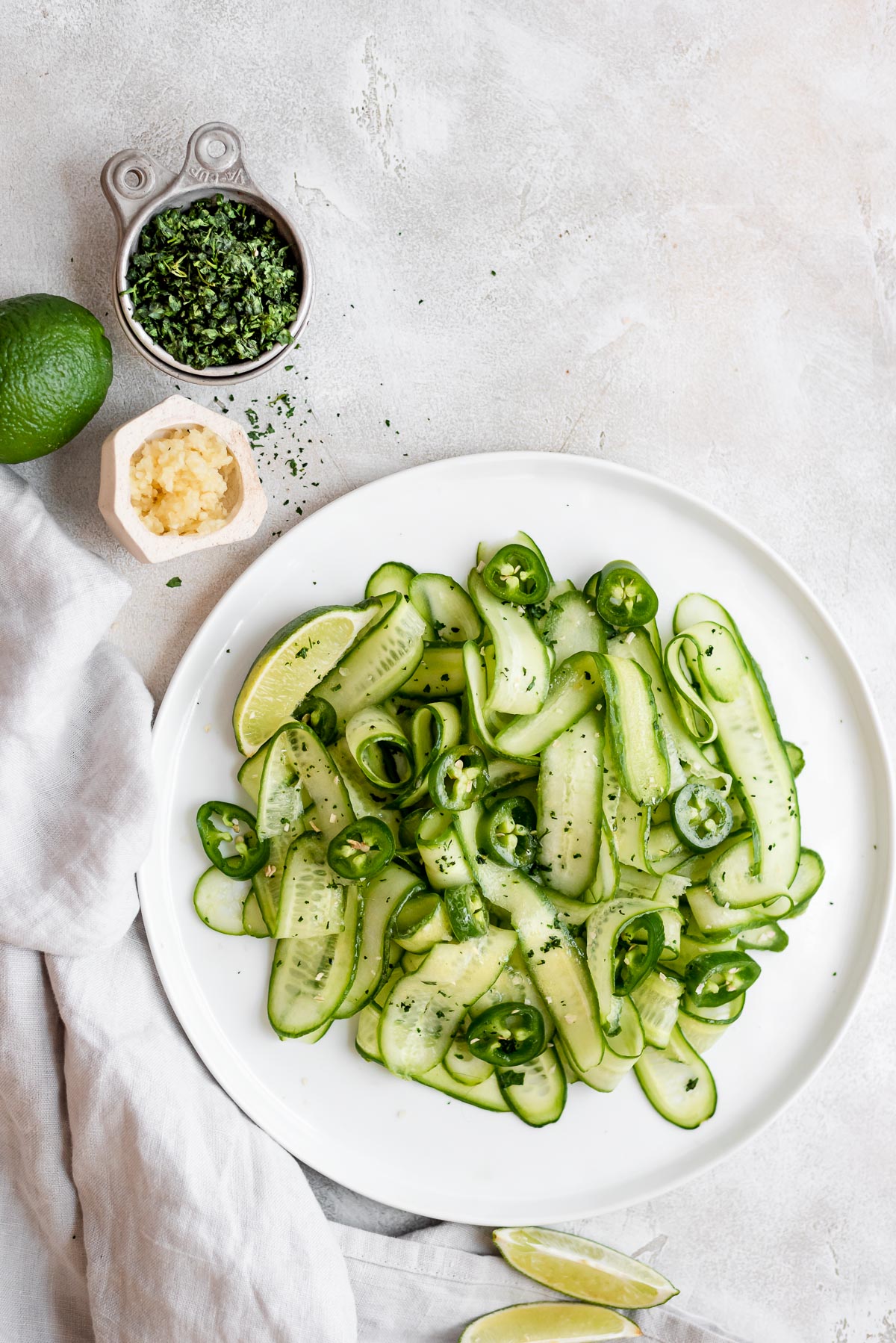 salad on a plate next to herbs and limes