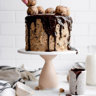 hand placing cookie dough truffle on cake