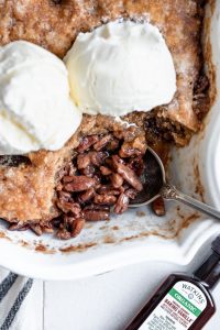 overhead close up pecan pie cobbler topped with ice cream in pan