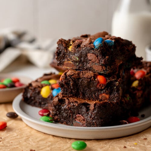 brownies stacked on plate alongside m&m candies